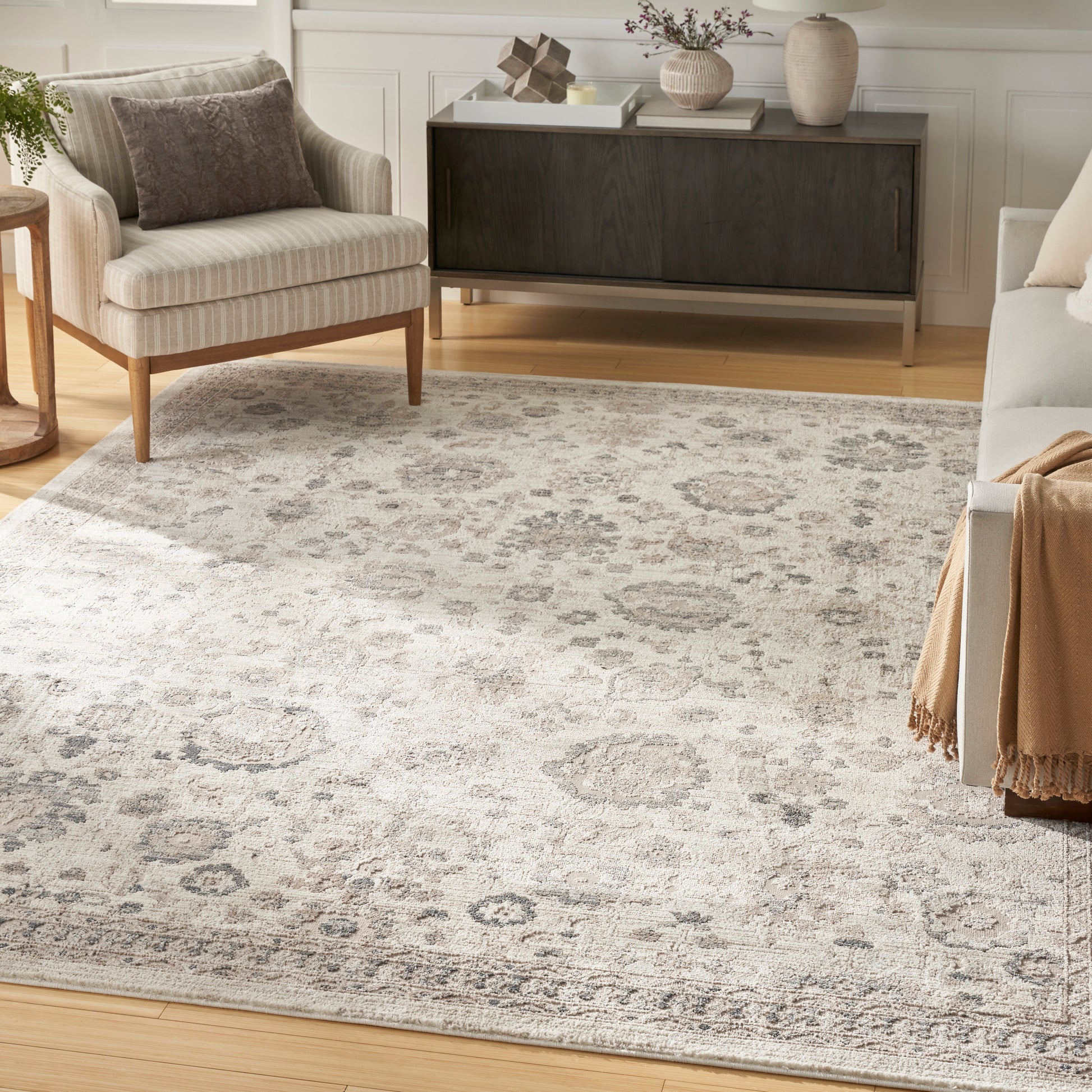 Large rectangular area rug with distressed traditional damask pattern in light gray and beige, in a contemporary living room.