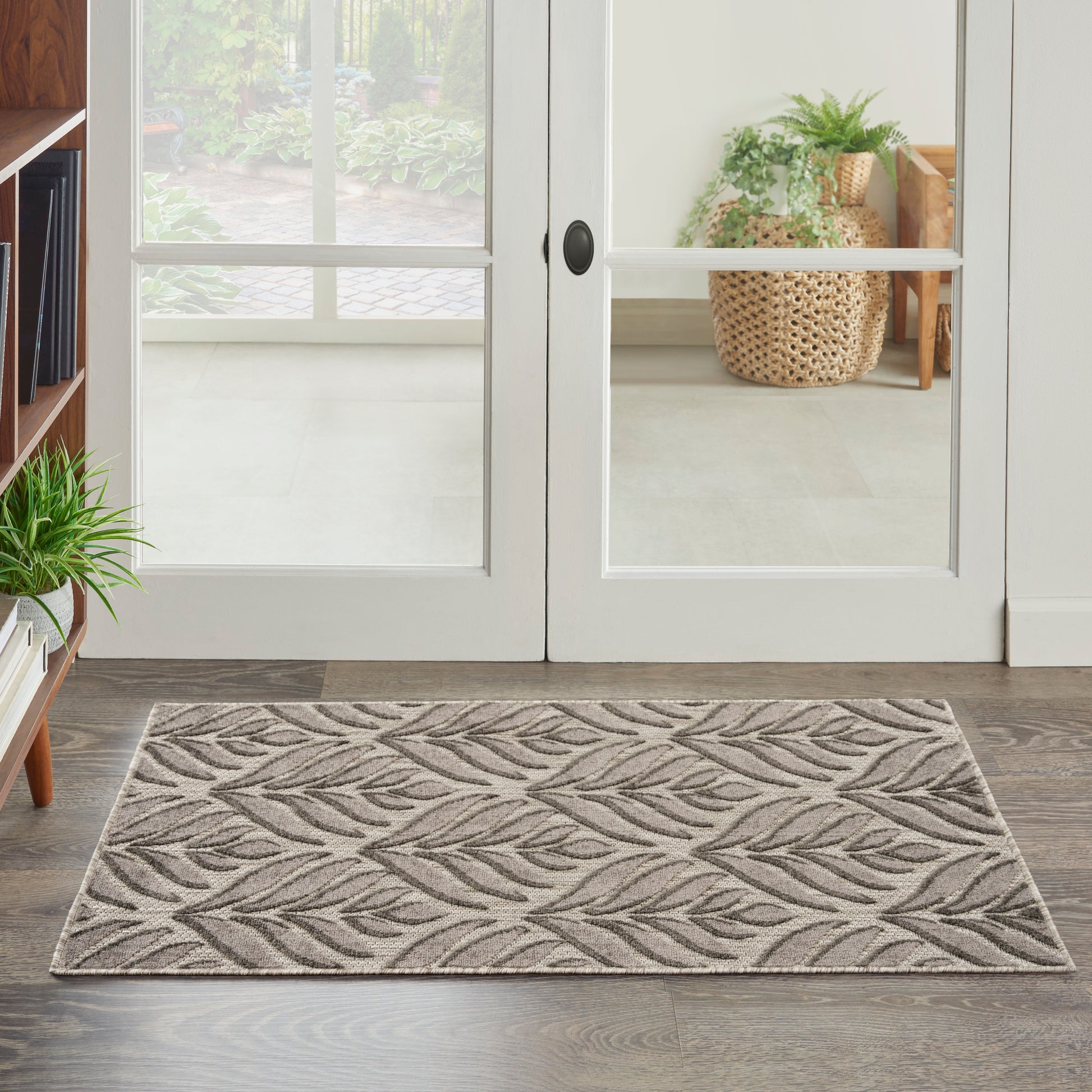 Neutral beige entry rug with a fern leaf pattern in front of white glass-paned double doors.