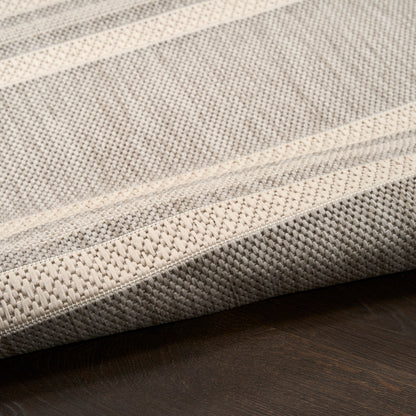Close-up of a beige and gray striped woven rug on dark wood floor.