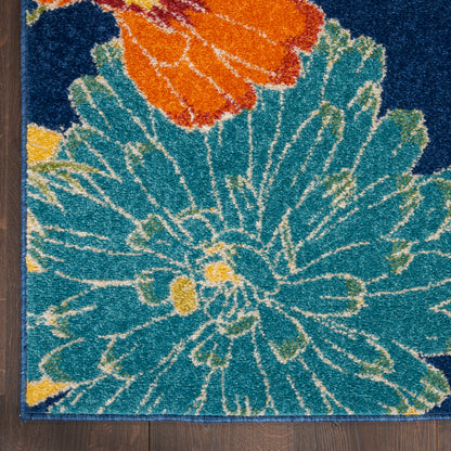 Tufted floral rug with teal petals and an orange bloom, yellow accents on a dark blue background, laid on a wooden floor.