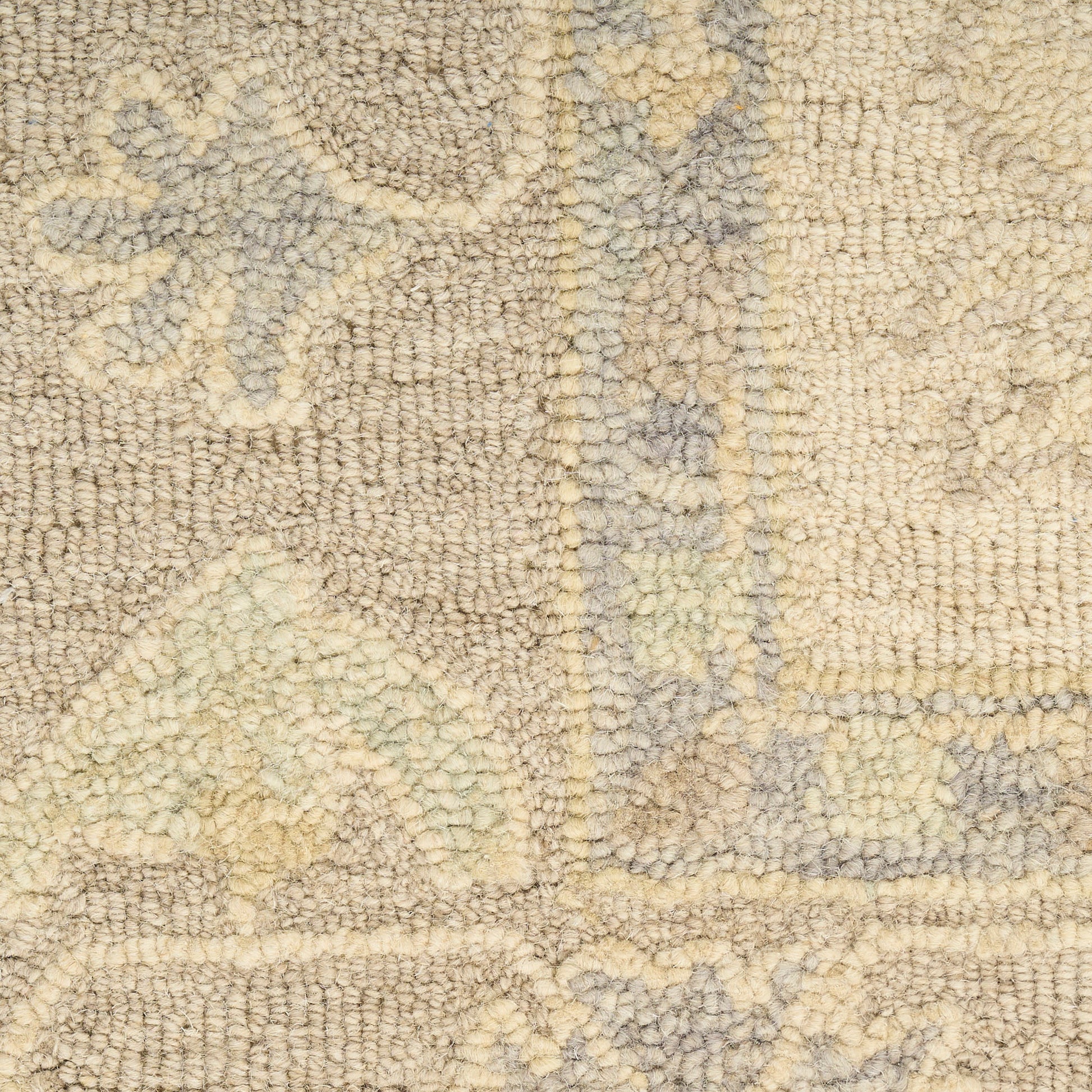 Beige shag rug close-up with pale blue-gray floral and geometric motif and thick soft pile.