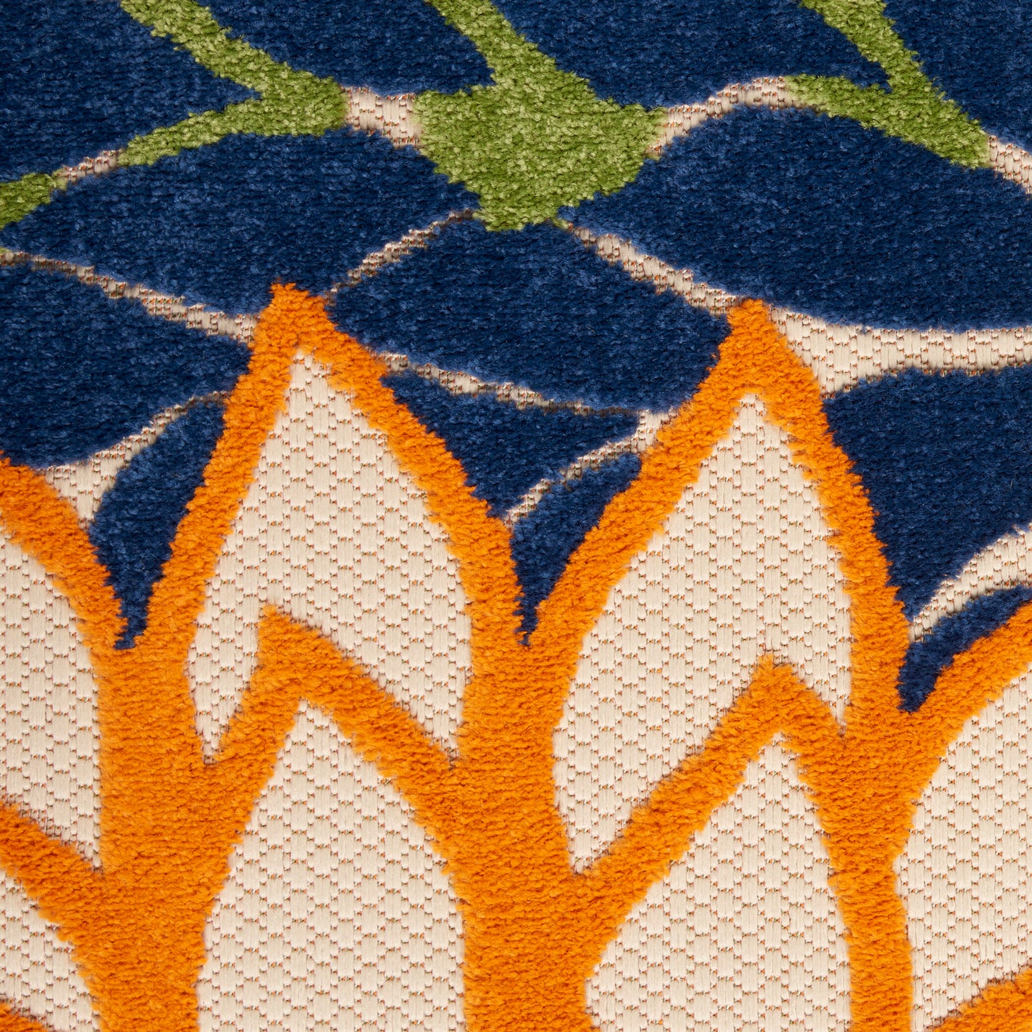 Close-up of a blue rug with bold orange flower petals, cream centers, and green stems; looped-pile texture.
