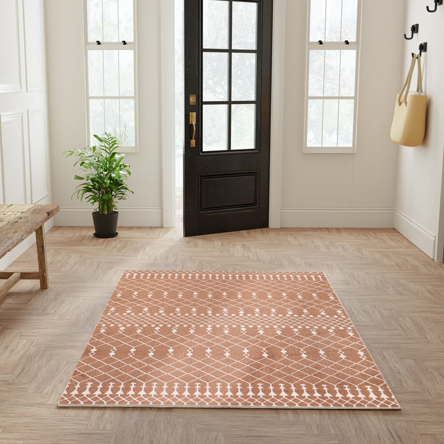 Rectangular terracotta rug with white geometric diamond lattice pattern in a bright entryway.
