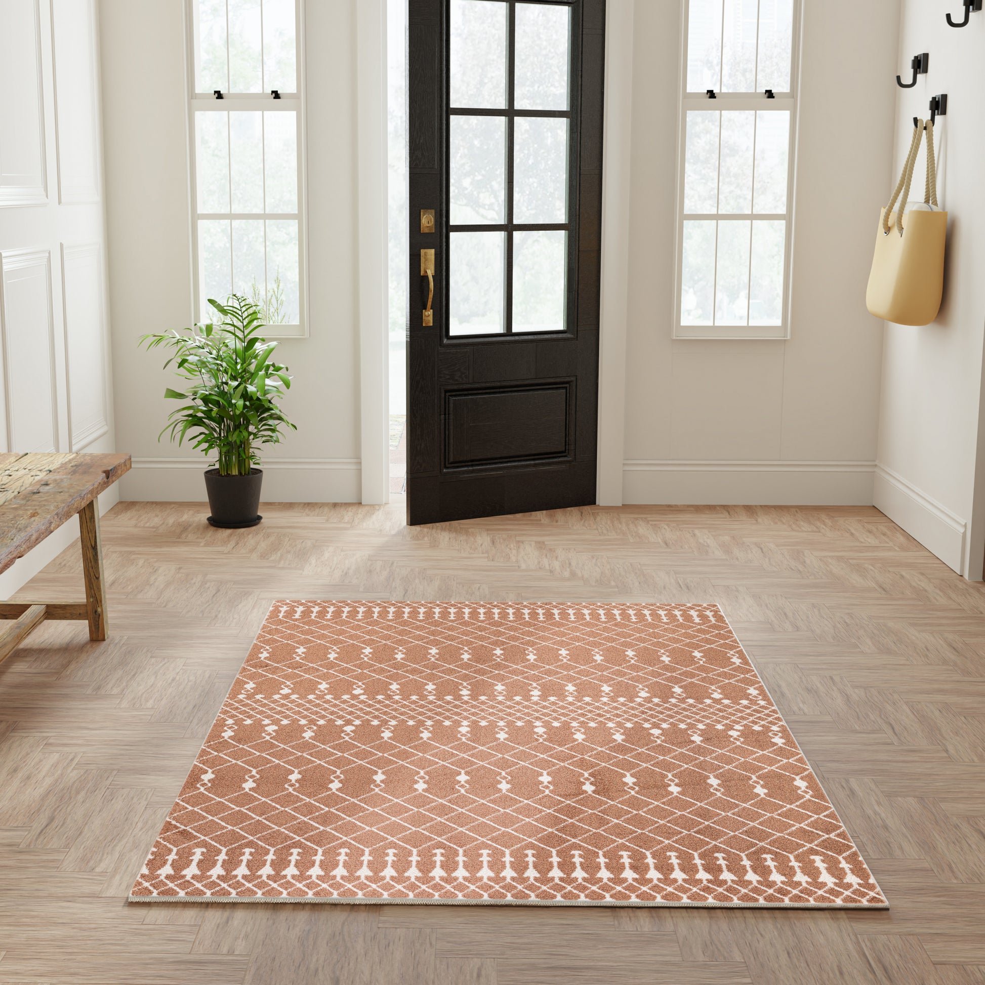 Rectangular terracotta rug with white geometric diamond lattice pattern in a bright entryway.