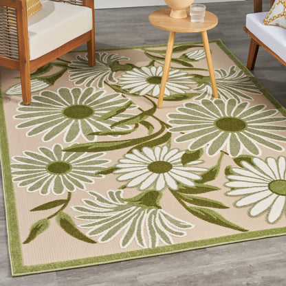 Beige outdoor rug with large white daisies and green stems, olive border; patio area with wooden chairs.