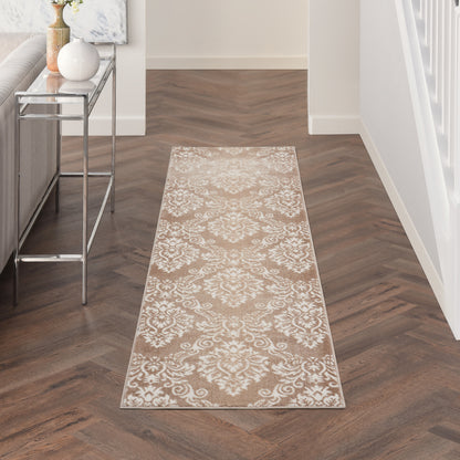 Beige damask runner rug on dark wood herringbone floor; glass console table left, white staircase railing right.