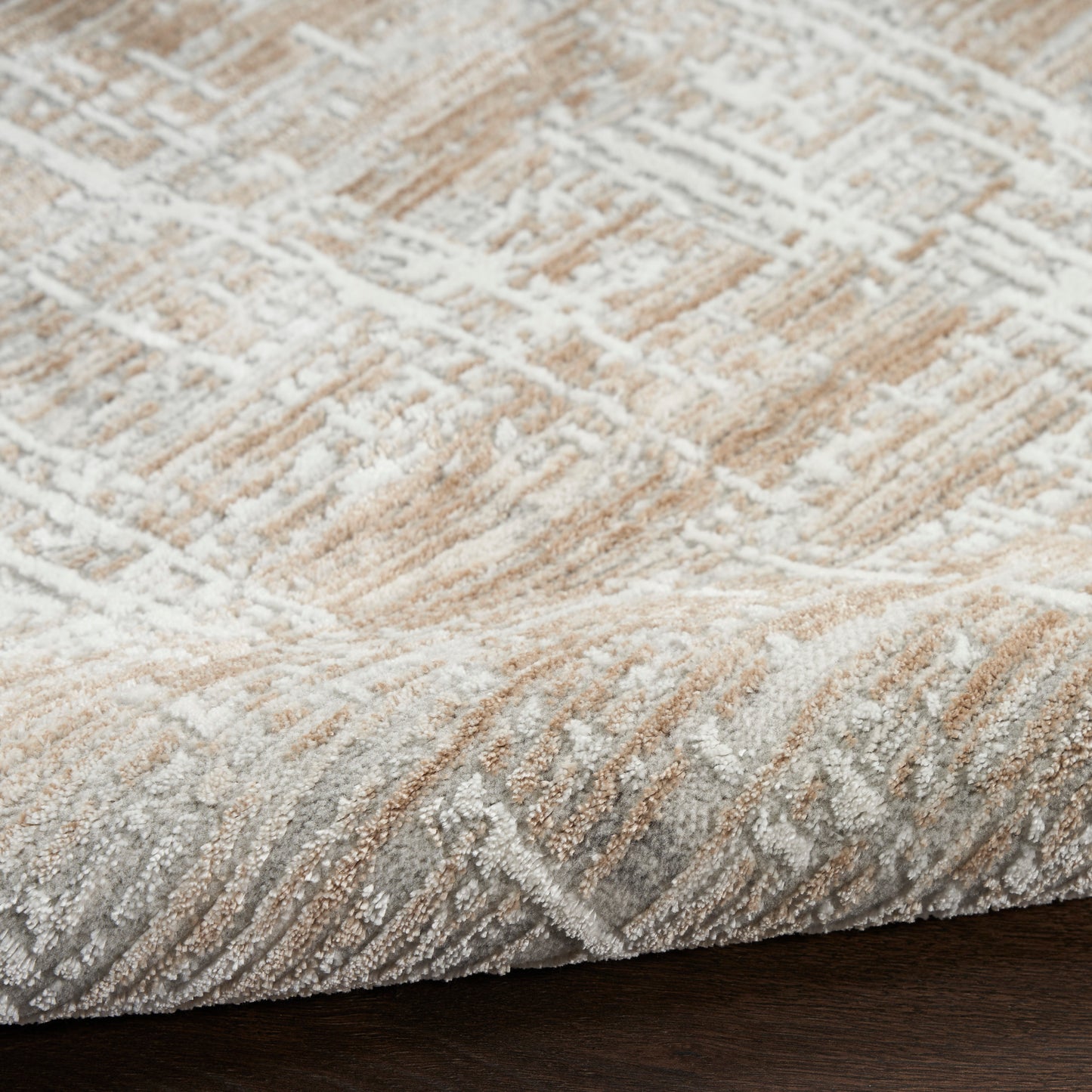 Beige and ivory patterned area rug with soft pile and subtle gray accents on dark wood floor.