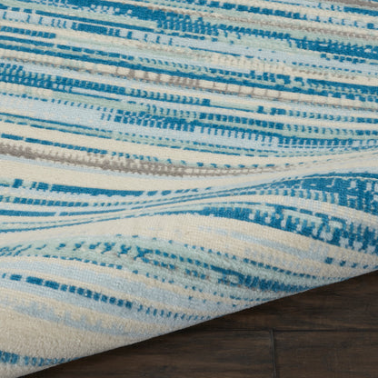 Blue and white striped woven rug with geometric patterns on dark wood floor.