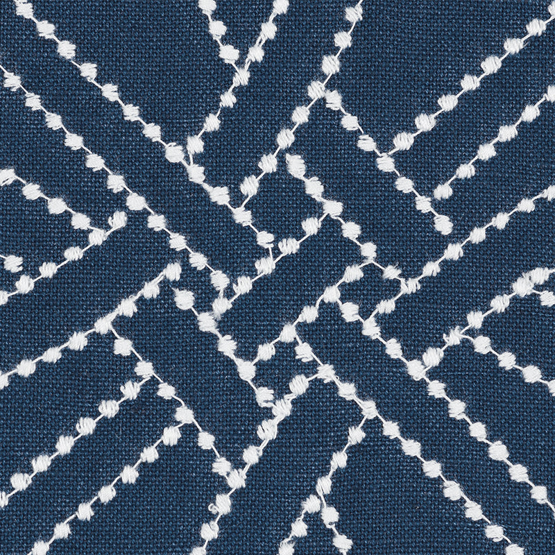 Navy blue fabric with white embroidered diamond lattice pattern; geometric texture.