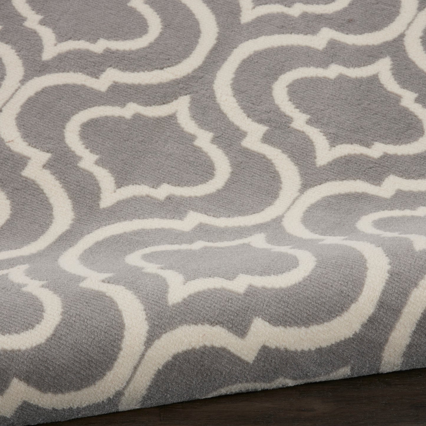Gray area rug with white trellis geometric pattern; soft textured surface, modern living room accent.