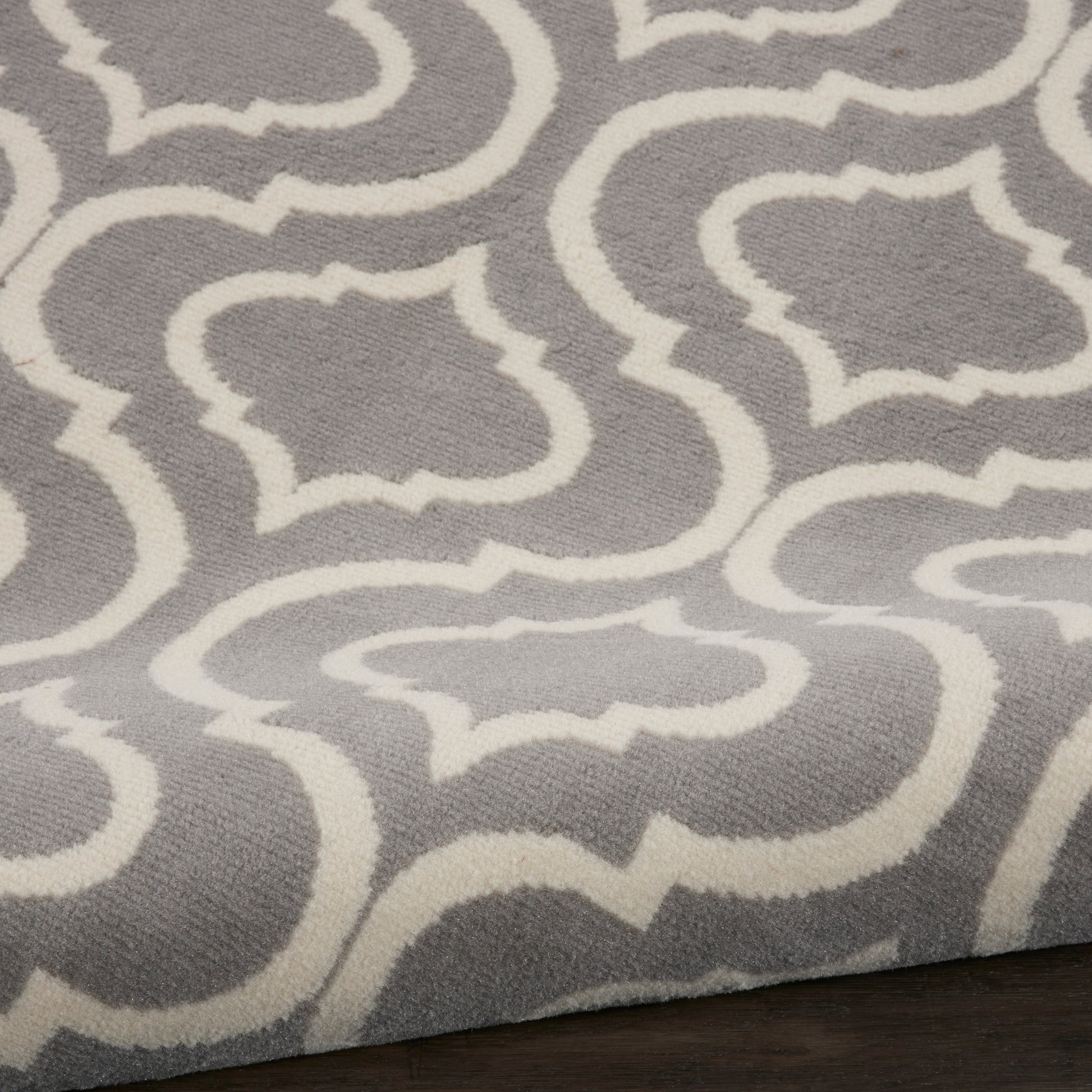 Gray area rug with white trellis geometric pattern; soft textured surface, modern living room accent.