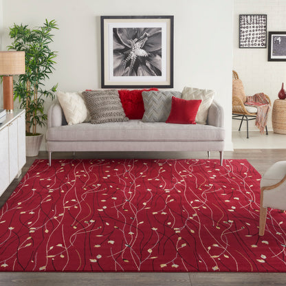 Living room with a red patterned area rug featuring white leaf-like vines, beige sofa with textured pillows, and framed art.