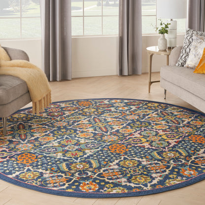 Round floral area rug with navy background and multicolor blossoms in orange, teal, yellow; living room with gray sofas.