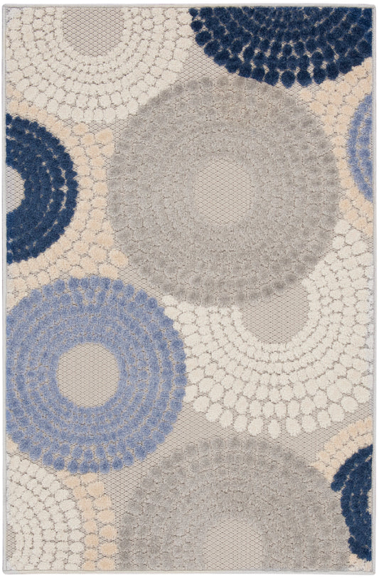 Rectangular textured shag rug with large circular concentric patterns in cream, beige, gray and navy.