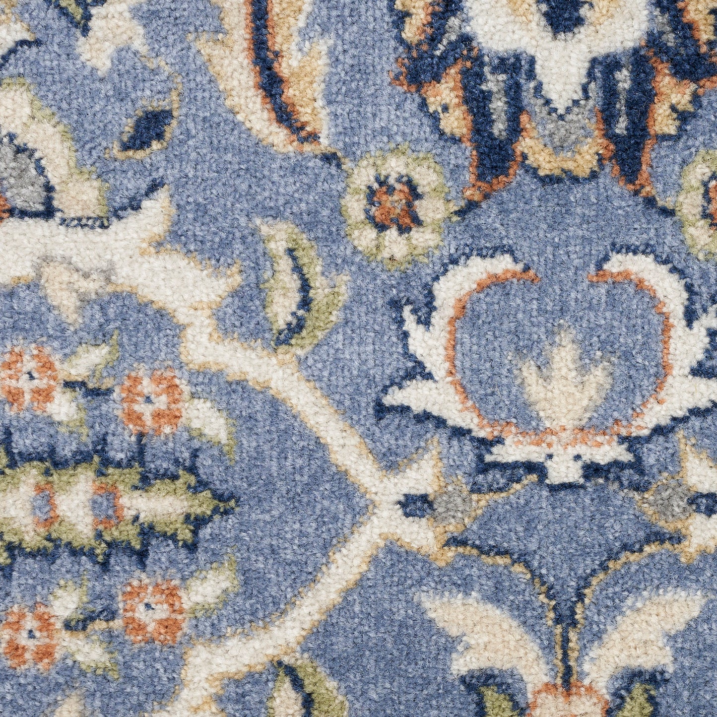 Close-up of blue Persian-style rug with ivory floral motifs & beige/orange accents, plush pile.