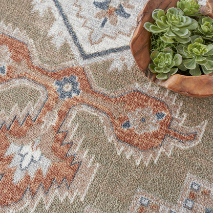 Geometric oriental rug in rust, sage, cream and blue with a wooden bowl holding green succulents.