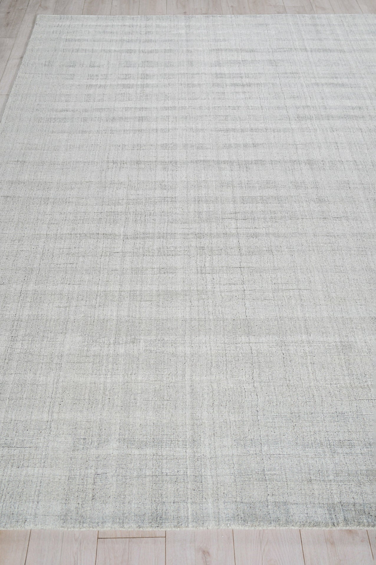 Light gray striped woven rug on a wood floor.