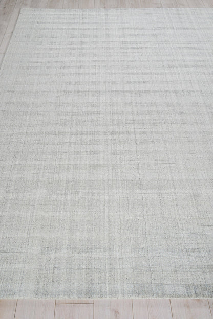 Light gray striped woven rug on a wood floor.