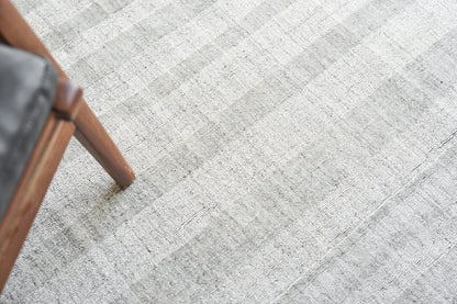 Partial view of a light gray textured rug.