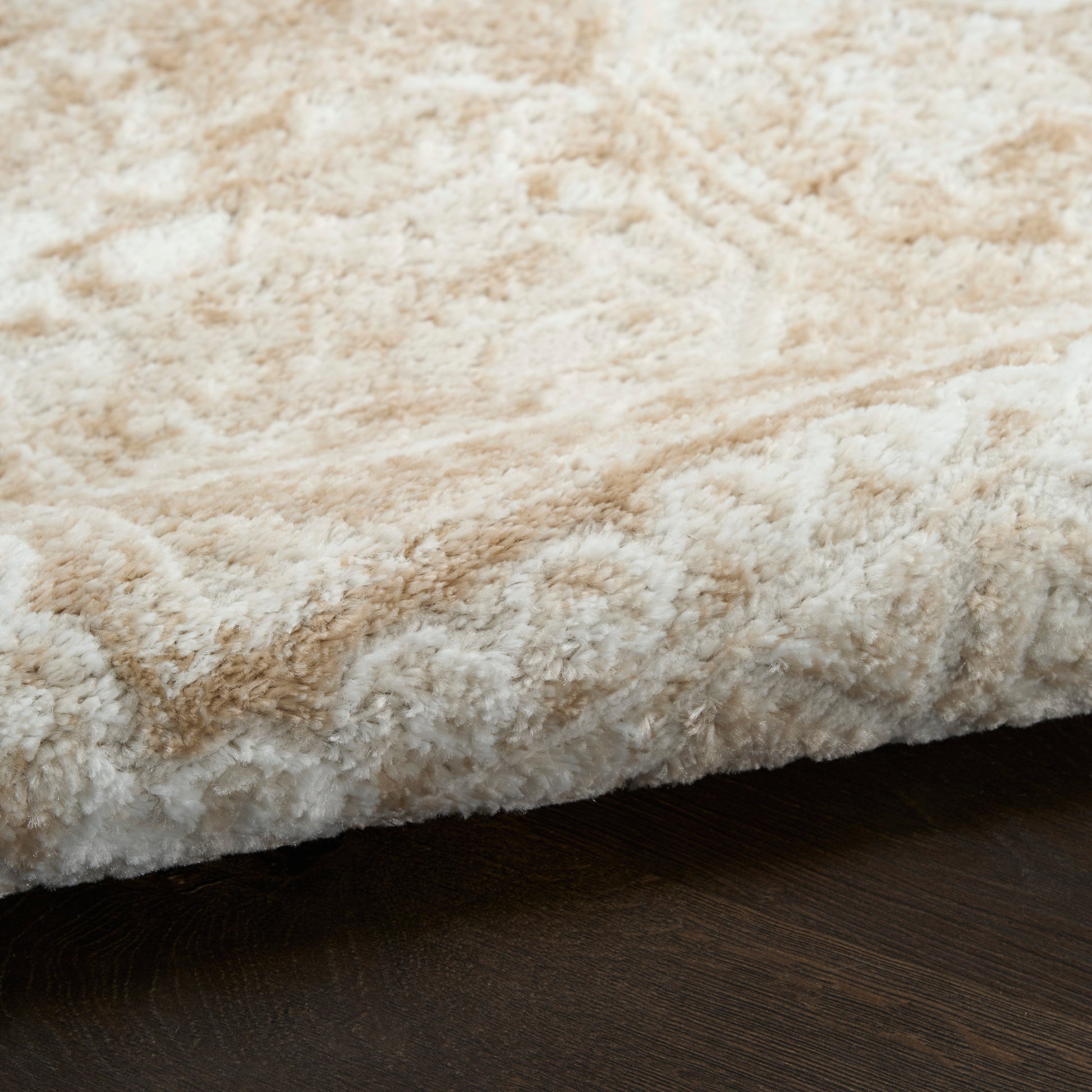 Cream beige shag rug with thick fluffy pile resting on dark wood floor.