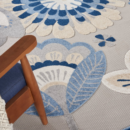Soft gray-blue patterned area rug with floral/leaf motifs in blue hues; wooden chair with blue cushion.