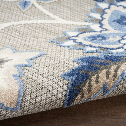Close-up of a woven area rug featuring a blue floral pattern on taupe background; wool blend, low-pile, decorative floor covering, 4' x 6'.