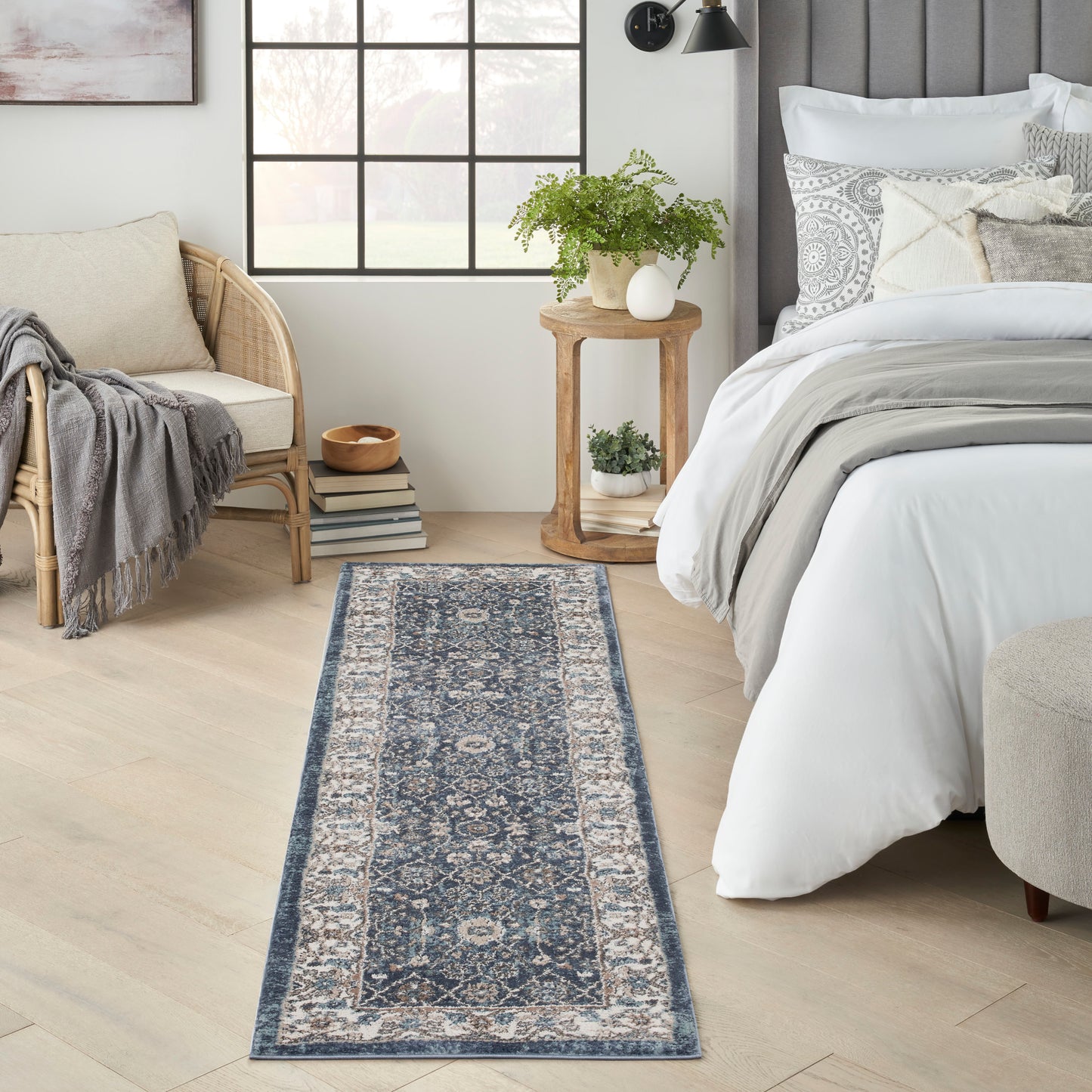 Navy & ivory oriental woven runner rug with intricate medallion pattern on light wood floor beside bed & seating