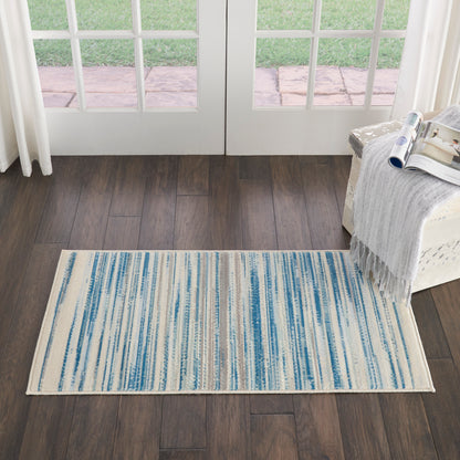 Rectangular woven rug with blue and cream vertical stripes on dark wood floor.
