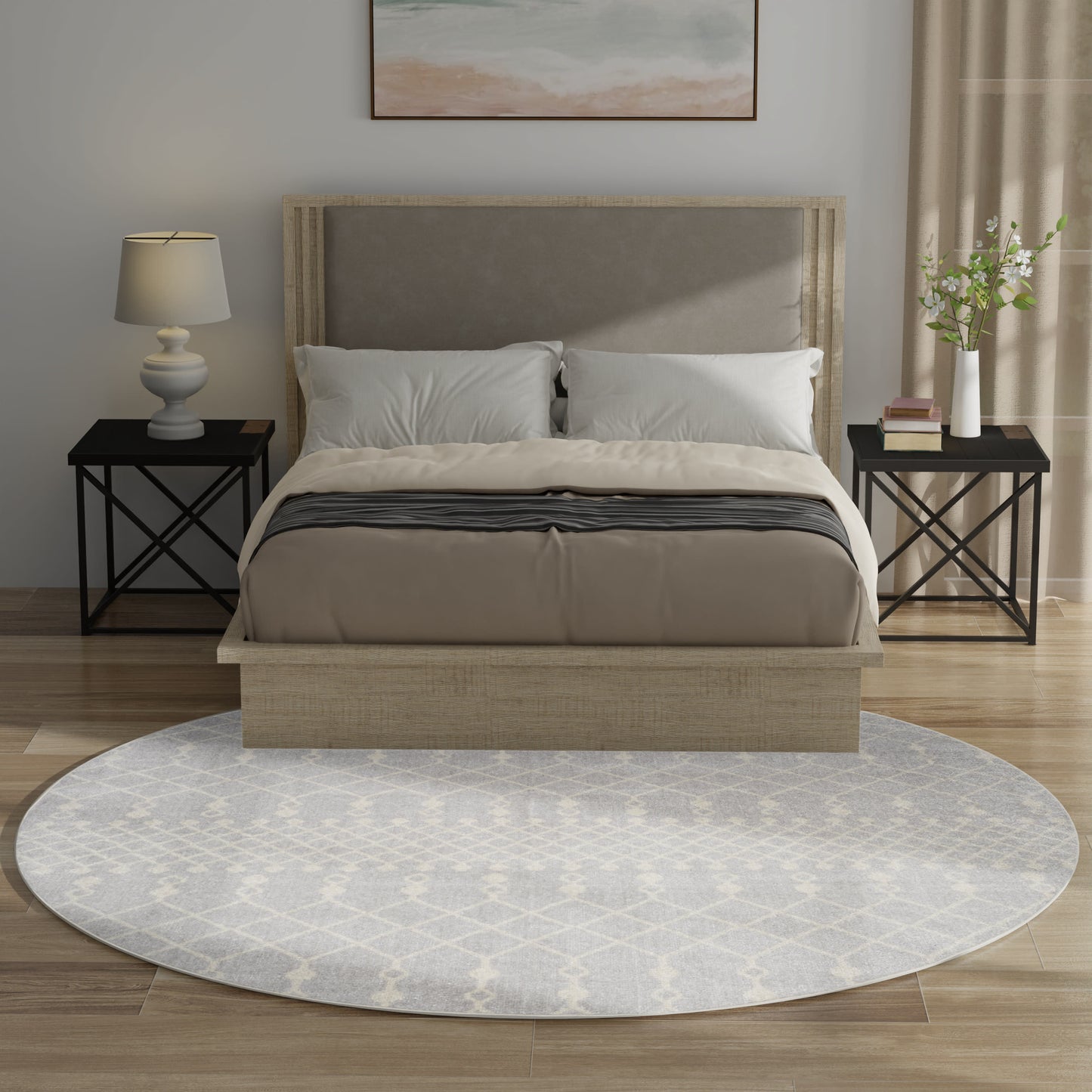 Round Bohemian rug in gray with a subtle pattern; in a bedroom scene with a beige upholstered bed with light wood frame, taupe bedding, white pillows, black metal nightstands, lamp and plant.