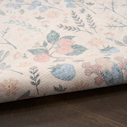 Pastel floral woven rug with pink, blue and green blossoms on ivory background, rolled on dark wood surface.