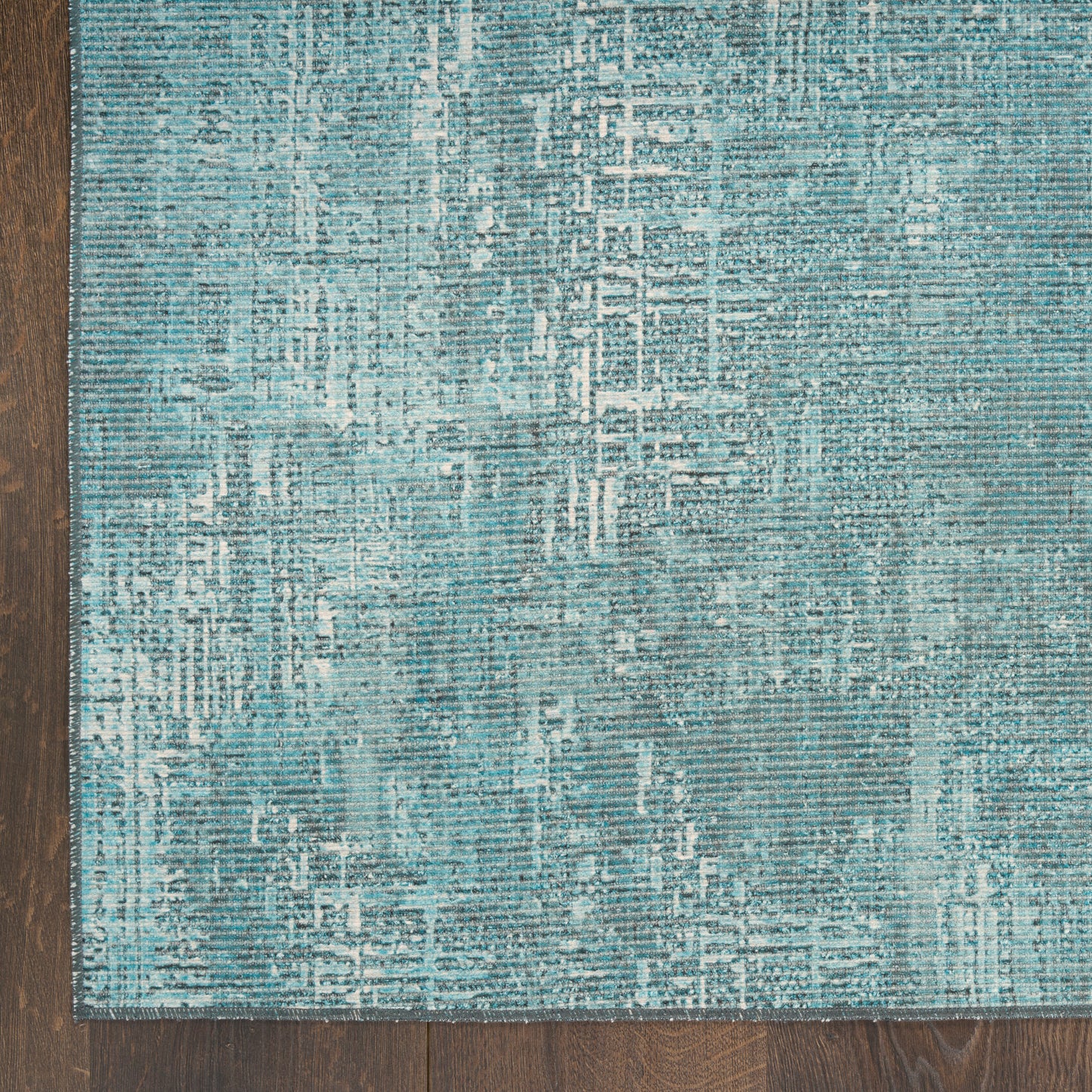 Teal distressed runner rug with abstract geometric grid pattern on dark wood floor.