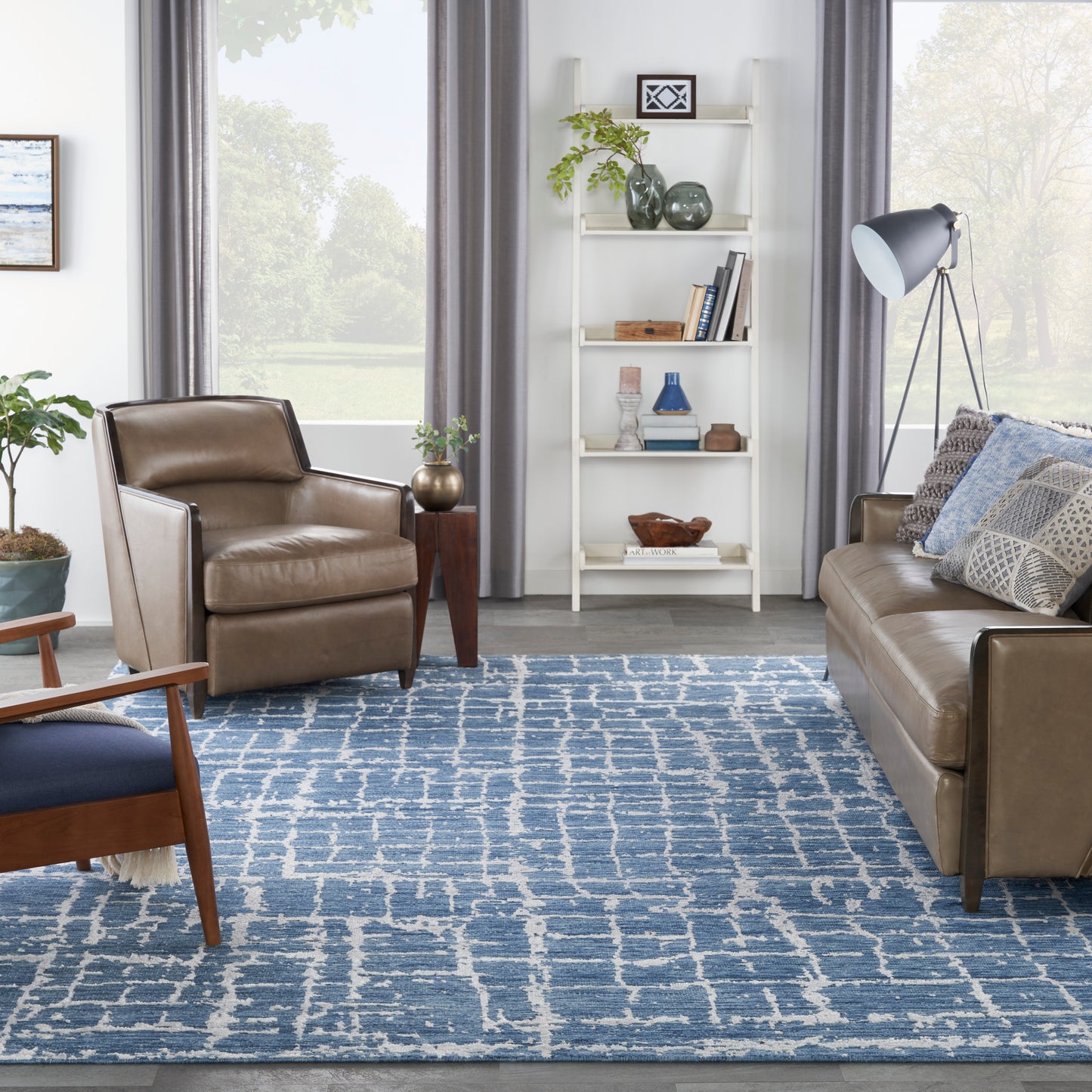Blue patterned modern rug in a bright living room with a white bookshelf and floor lamp.