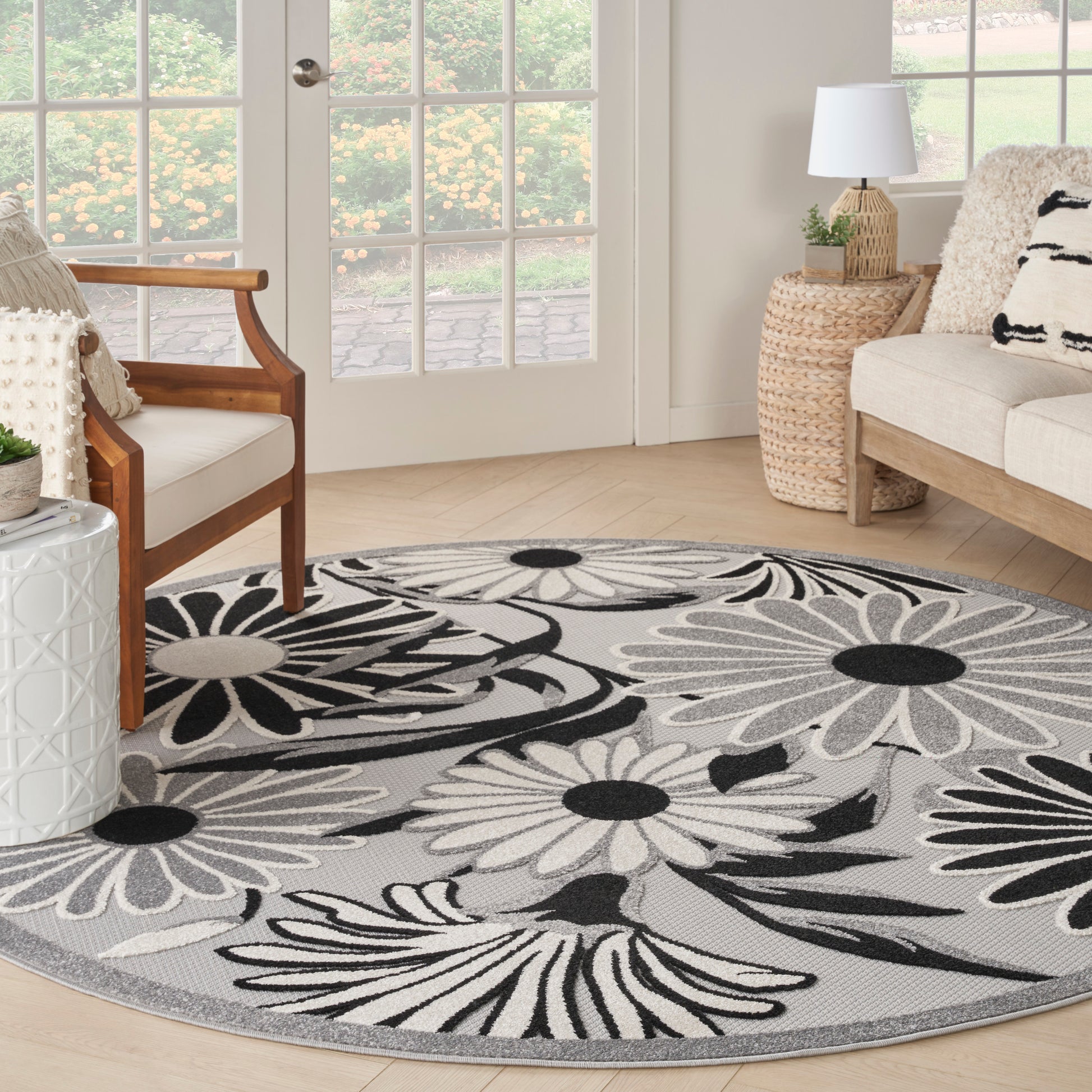 Round grey rug with bold black-and-white floral petals in a bright living room.