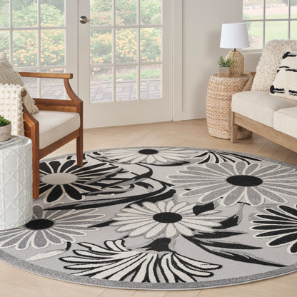 Round grey rug with bold black-and-white floral petals in a bright living room.