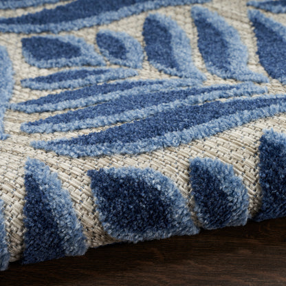 Close-up of a plush blue tufted rug with beige base and abstract leaf pattern.