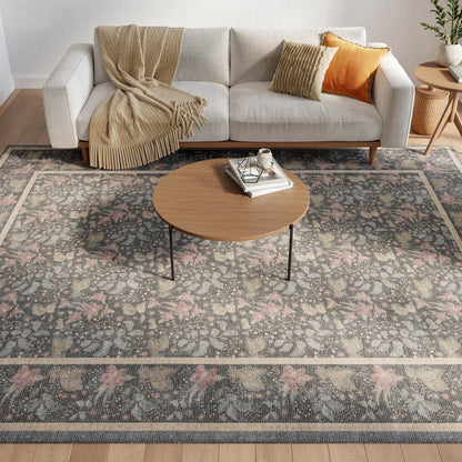 Light gray sofa with beige throw and orange pillow, round wood coffee table on a vintage floral rug in a modern living room.