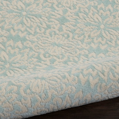 Light blue rug with a white raised floral damask pattern and folded edge, 2' x 4'.