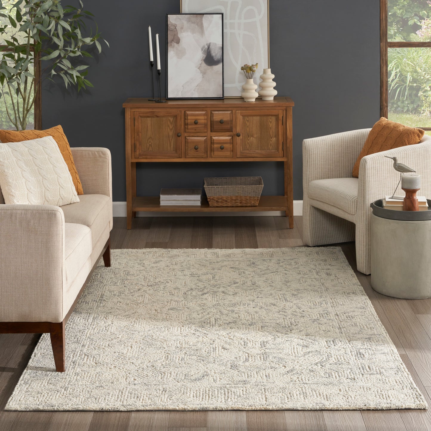 Beige mid-century living room with warm wood sideboard against a dark wall, cream textured rug, and neutral fabric chairs.