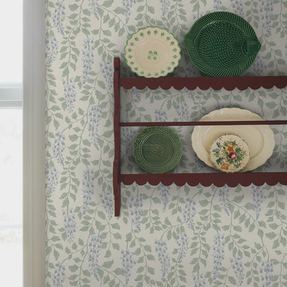 Wooden maroon wall shelf with scalloped edge, displaying green ceramic plates and a floral beige plate on botanical wallpaper.