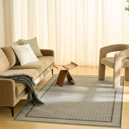 Beige fabric sofa with white textured pillow, curved wood coffee table, beige armchair, gray patterned rug, light curtains.