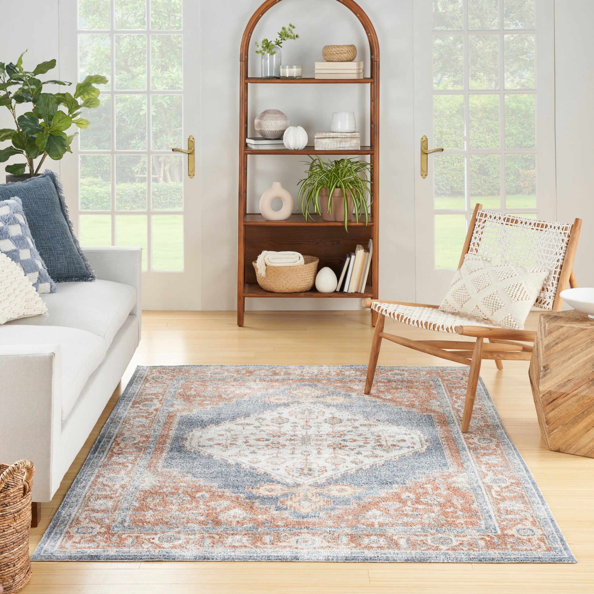 Vintage 4' x 6' blue and orange patterned rug in a sunlit living room with a light gray sofa and plants.