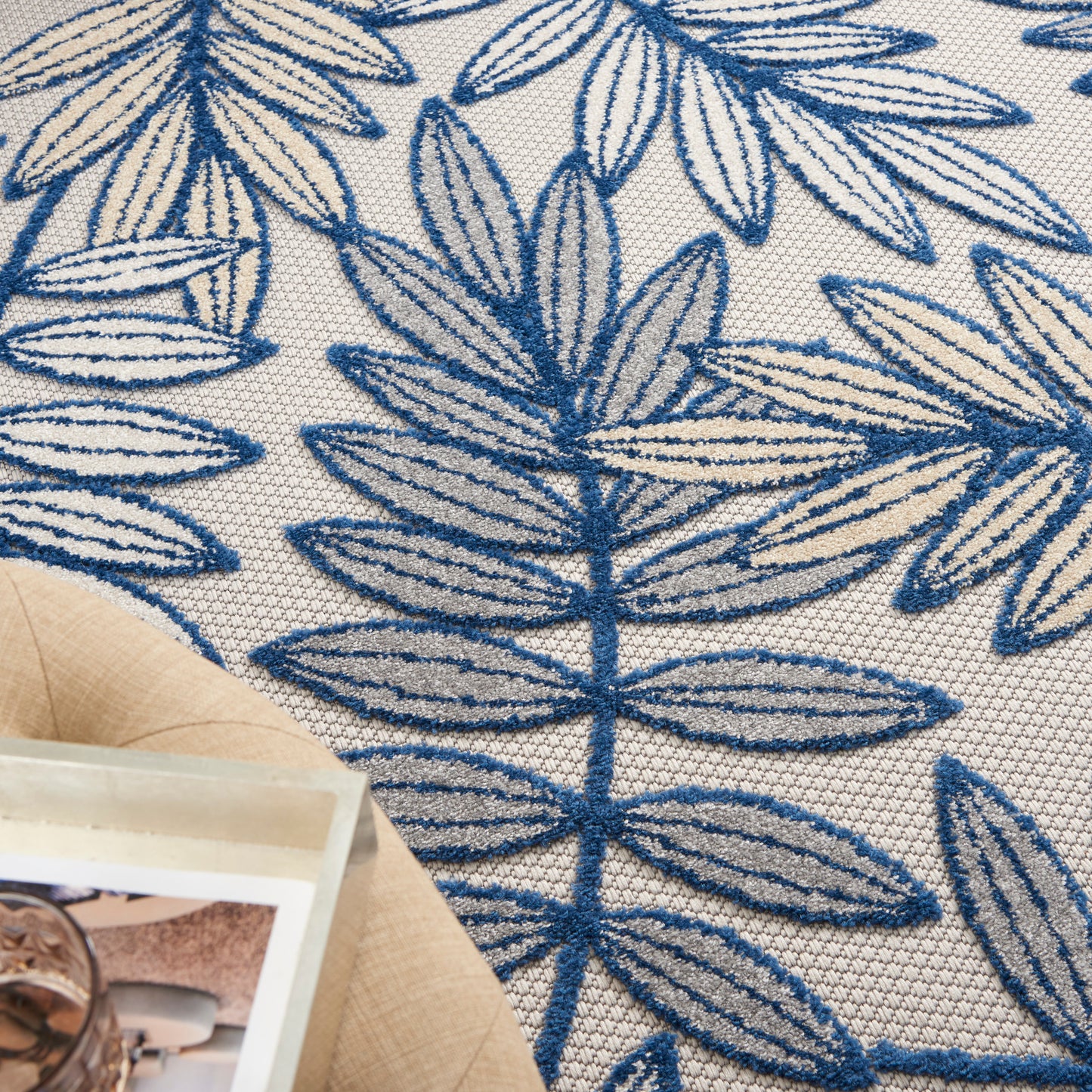 Beige rug with blue embroidered botanical leaf pattern, 4' x 6'.