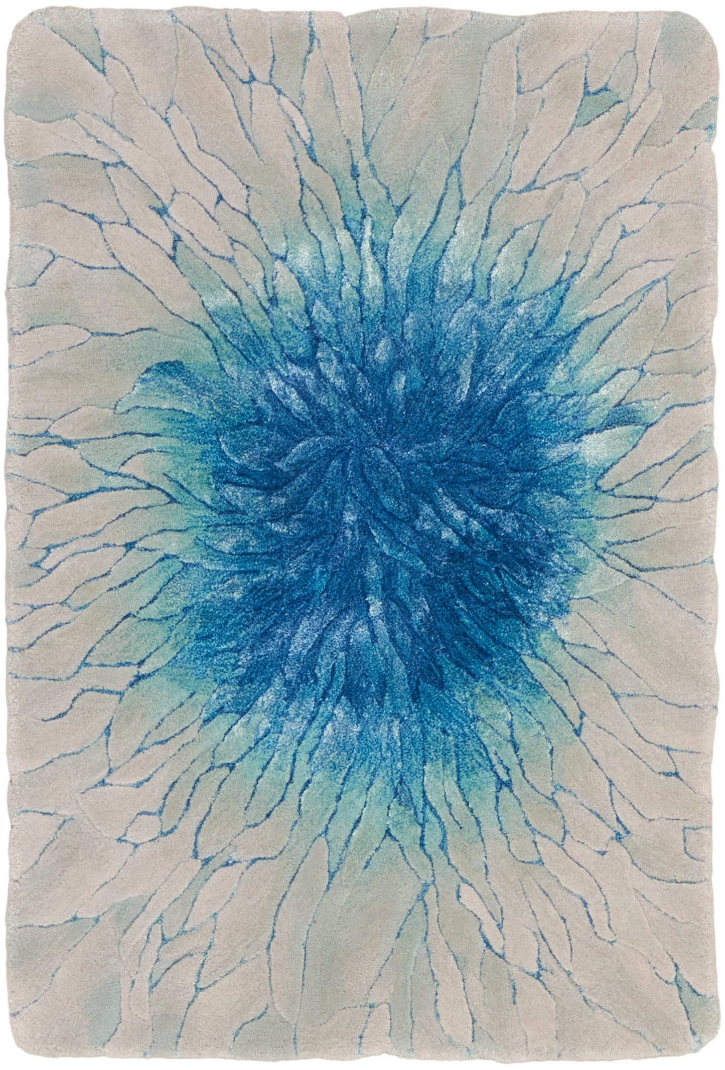 Rectangular blue burst rug on cream backdrop; plush shag with radiating blue spokes, modern coastal style.