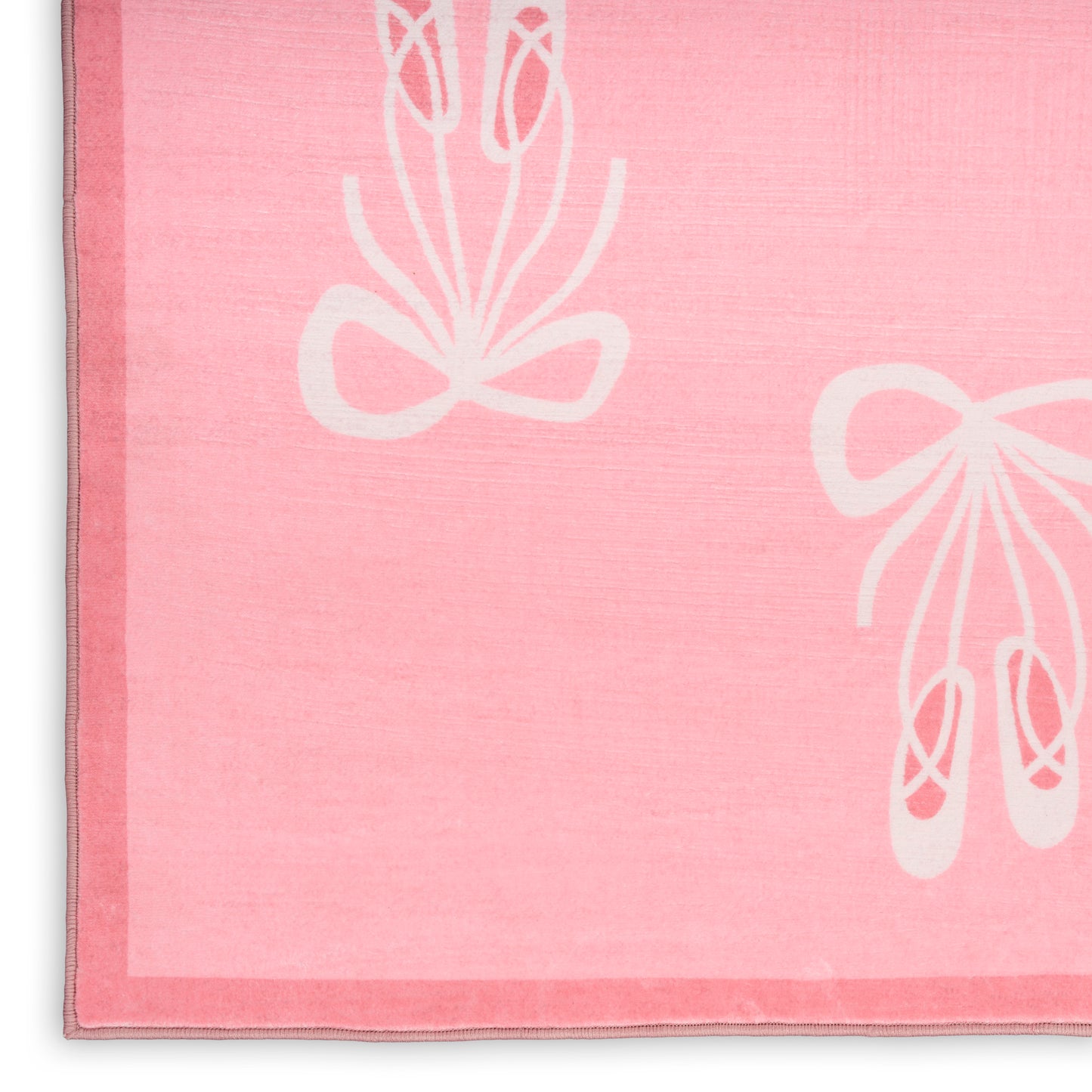 Pink kids rug with white ballet shoe and bow motifs; soft pile.