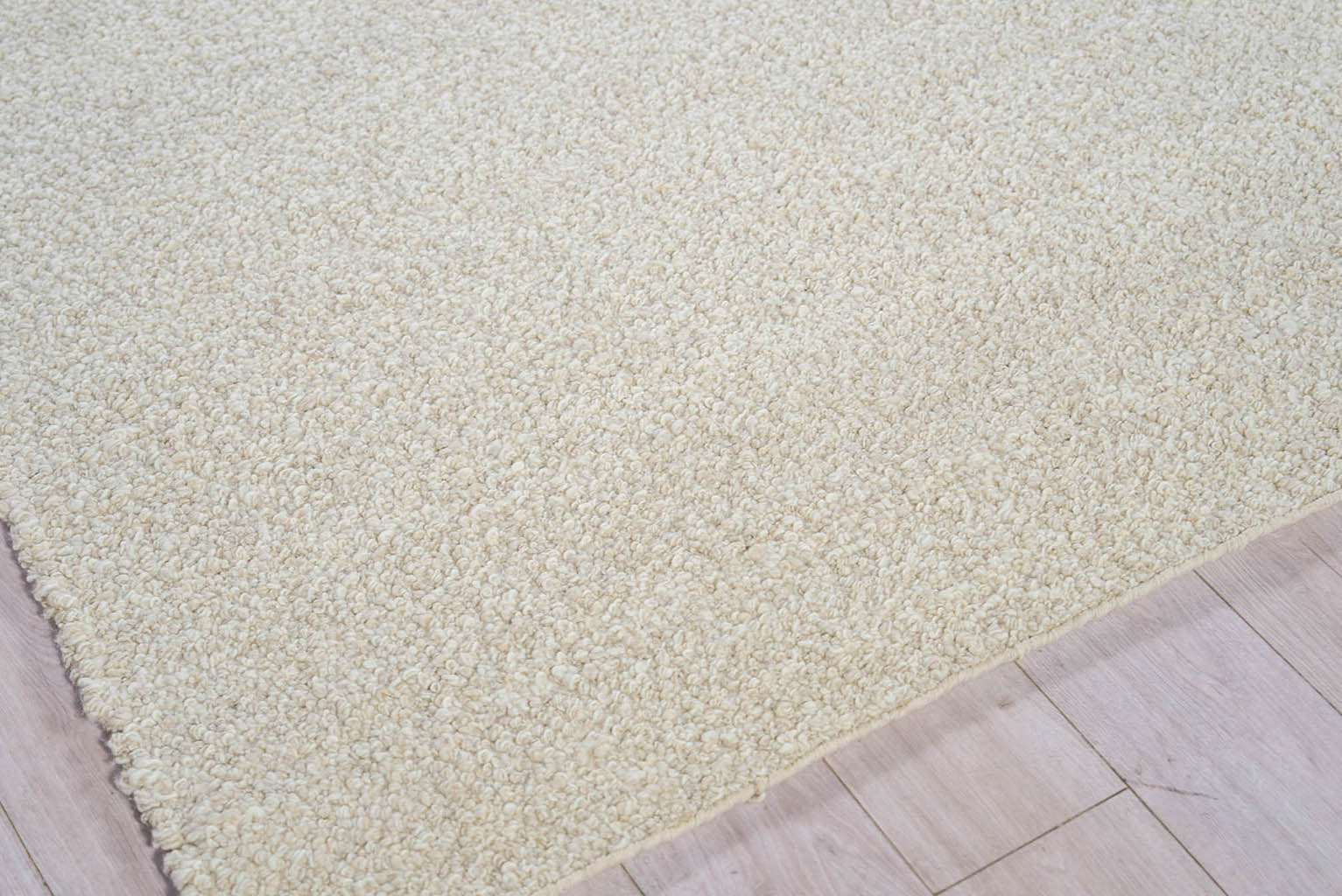 Cream-beige shag rug with thick plush pile on light wood floor; rectangular living room rug.