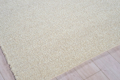 Cream-beige shag rug with thick plush pile on light wood floor; rectangular living room rug.