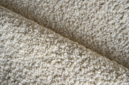 Cream indoor hand-loomed rug with a plush, curly texture.