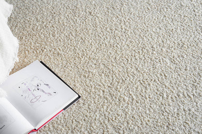 Beige shag rug with an open art book showing a line-drawn face; white pages, black spine, red edge.