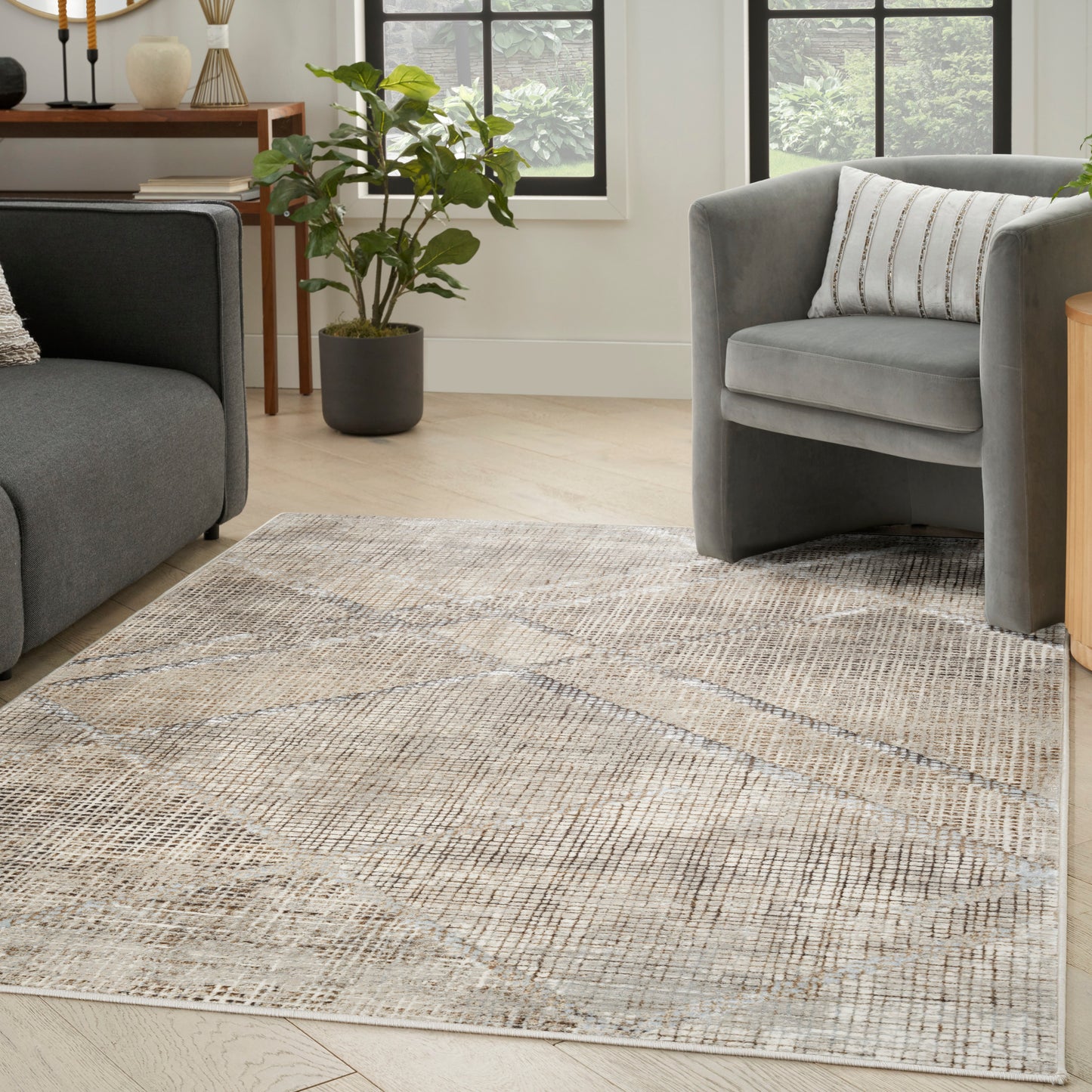 Geometric beige-gray area rug on light wood floor between two gray upholstered sofas and a potted plant in a modern living room.