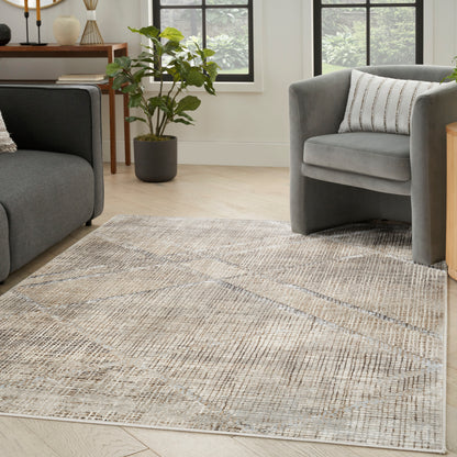 Geometric beige-gray area rug on light wood floor between two gray upholstered sofas and a potted plant in a modern living room.
